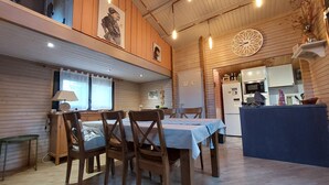 A cozy, rustic dining area with wooden furniture and a kitchen in the background.