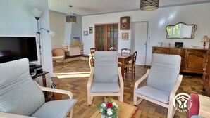 A spacious living room with a television, comfortable seating, a dining area, and a kitchen. - Bright Gîte near Laval, 3 bedrooms, large grounds, ideal for families (L'Huisserie)