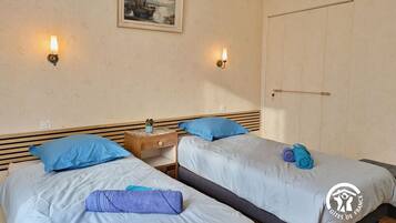 A hotel room with two beds, a nightstand, a painting on the wall, and a wardrobe.