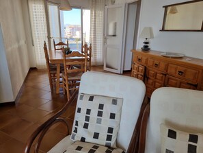 A hotel room with a dining area, a wooden cabinet, and a view of the city through the window. - Comfortable apartment with terrace 200m from the beach (L'Escala)