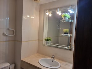 A bathroom with a white sink, a mirror with lights, and a towel rack. - Apartment in L'Escala with pool and parking, 600m from the beach (L'Escala)