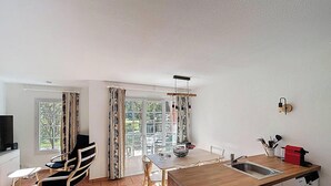 Eine moderne Küche mit Essbereich, großen Fenstern und Blick auf Grünflächen.