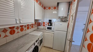 A compact kitchen with a washing machine, a microwave, and a refrigerator. - Apartment in L'Escala with terrace and pool, near the beach (L'Escala)
