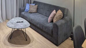 Una sala de estar moderna con un sofá gris, una mesa redonda de centro y un cuadro en la pared.