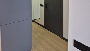 Un pasillo con un armario gris, una puerta oscura y un interruptor de luz en la pared.
