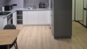 Una cocina moderna con armarios blancos, horno empotrado, pileta y un refrigerador grande.