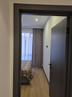Ein Hotelzimmer mit einem Bett, Holzboden und einer Tür zu einem weiteren Raum.