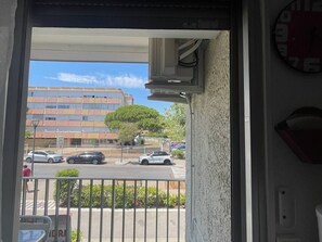 A view from a balcony with a building, cars, and a tree in the background. - Air-conditioned studio near the thermal baths (Balaruc-les-Bains)