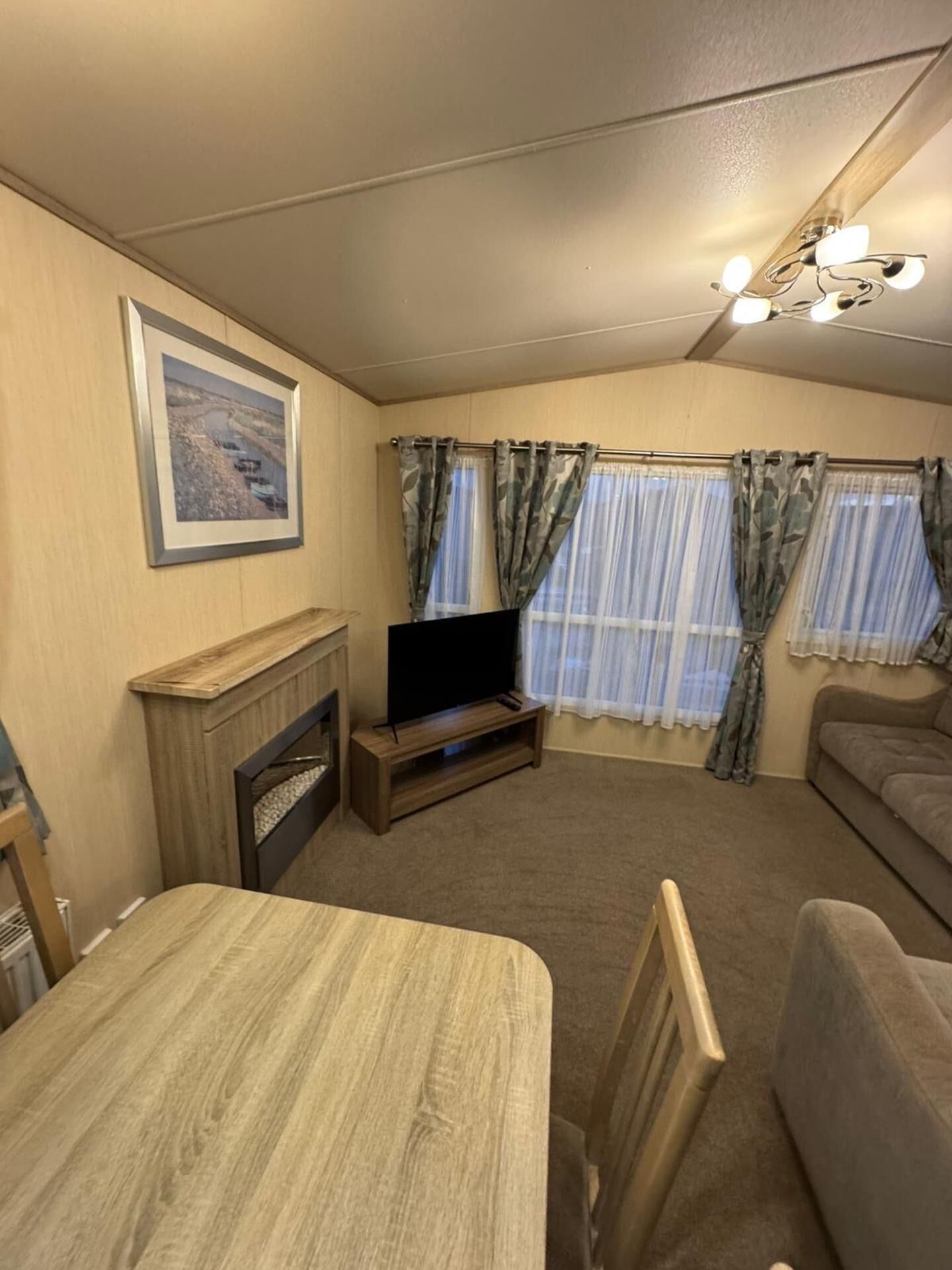A room with a television, a fireplace, a sofa, and a dining table.