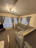 Un espacio habitable pequeño con un sofá, una televisión y cortinas en las ventanas.