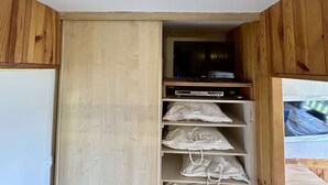 Ett rum med ett träskåp, en tv på en hylla och en vit taklampa.