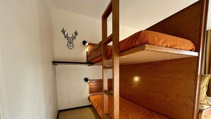Une chambre avec un lit superposé, une tête de lit en bois et une décoration murale représentant une tête de cerf.