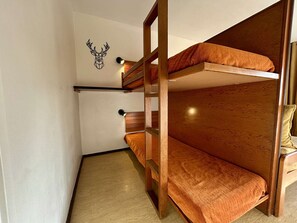 Ein Schlafraum mit Etagenbetten, einem Holzkopfteil und einer an der Wand befestigten Dekoration einer Hirschschädel.