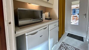 Une petite cuisine équipée d’un four à micro-ondes, d’une machine à café et d’un petit réfrigérateur.