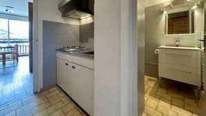 Une cuisine moderne dotée d’une cuisinière intégrée, d’une hotte aspirante et d’une petite fenêtre située au-dessus de l’évier.