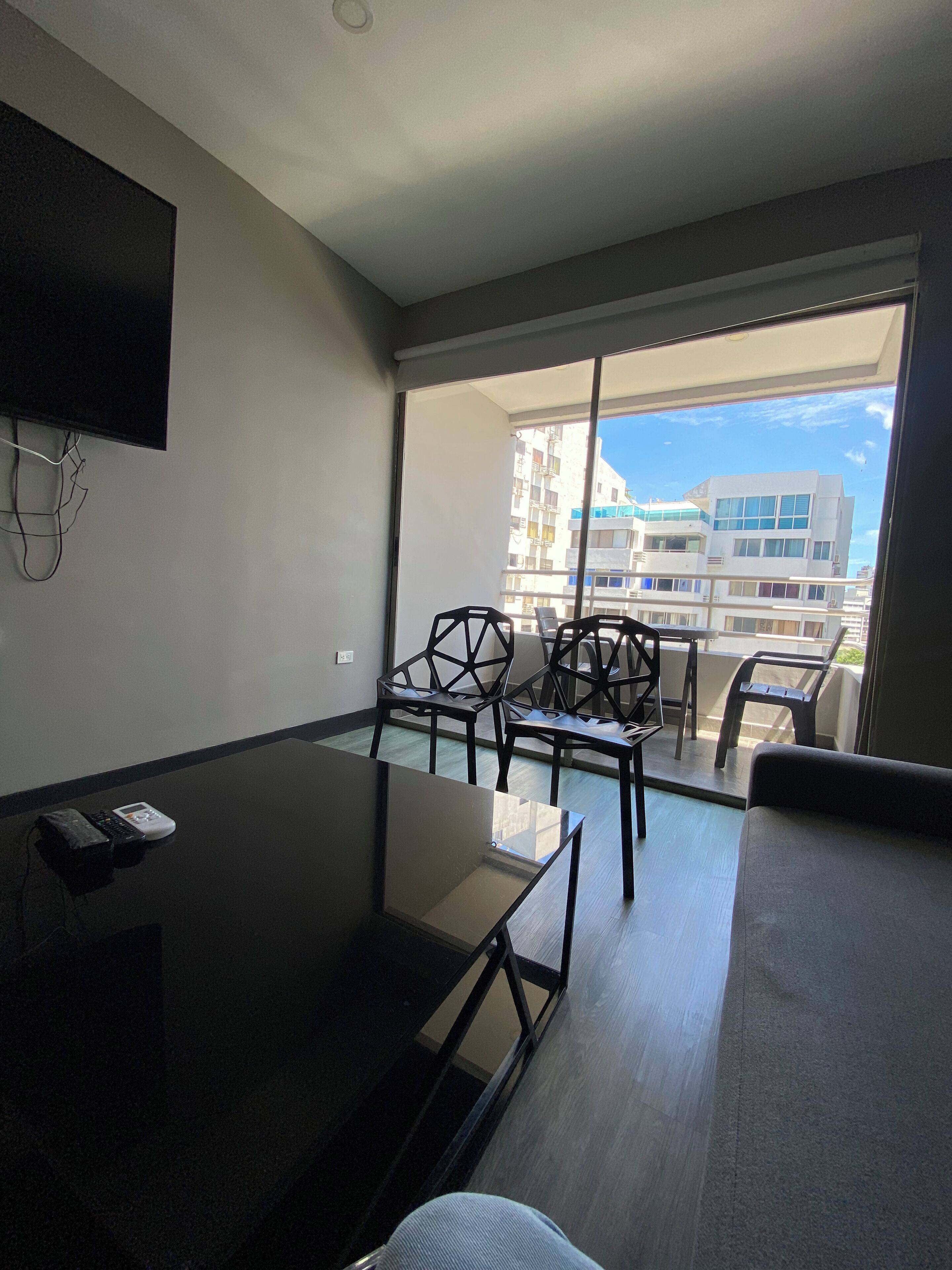 Una habitación moderna con una mesa de vidrio, sillas, un sofá y un televisor montado en la pared.