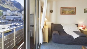 A hotel room with a bed, a nightstand, a lamp, and a view of a mountain and a road with cars. - Studio cabin 4 people at slope base in Gourette (Gourette)