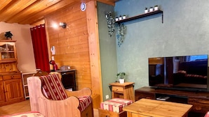 Uma sala de estar aconchegante com móveis de madeira, uma televisão e uma estante com plantas.