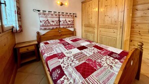 Quarto com painéis de madeira, com uma cama, mesa de cabeceira, guarda-roupa e luminária fixada na parede.