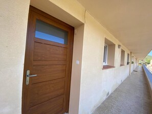 A corridor with a wooden door, windows, and a balcony. - Lovely T2 Cabin - Near Beach & Shops (Bormes-les-Mimosas)