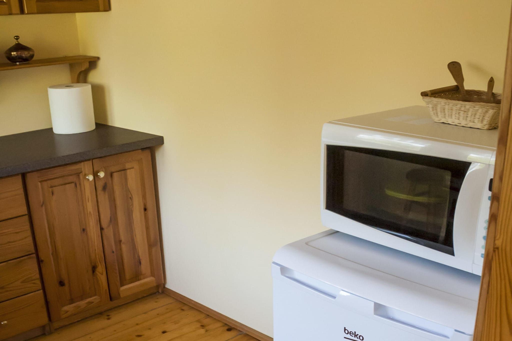 Une cuisine avec des meubles de rangement en bois, un four à micro-ondes et un panier posé sur le dessus.