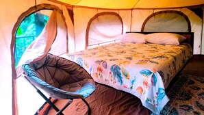 Una tienda de campaña con una cama, una silla y una ventana.