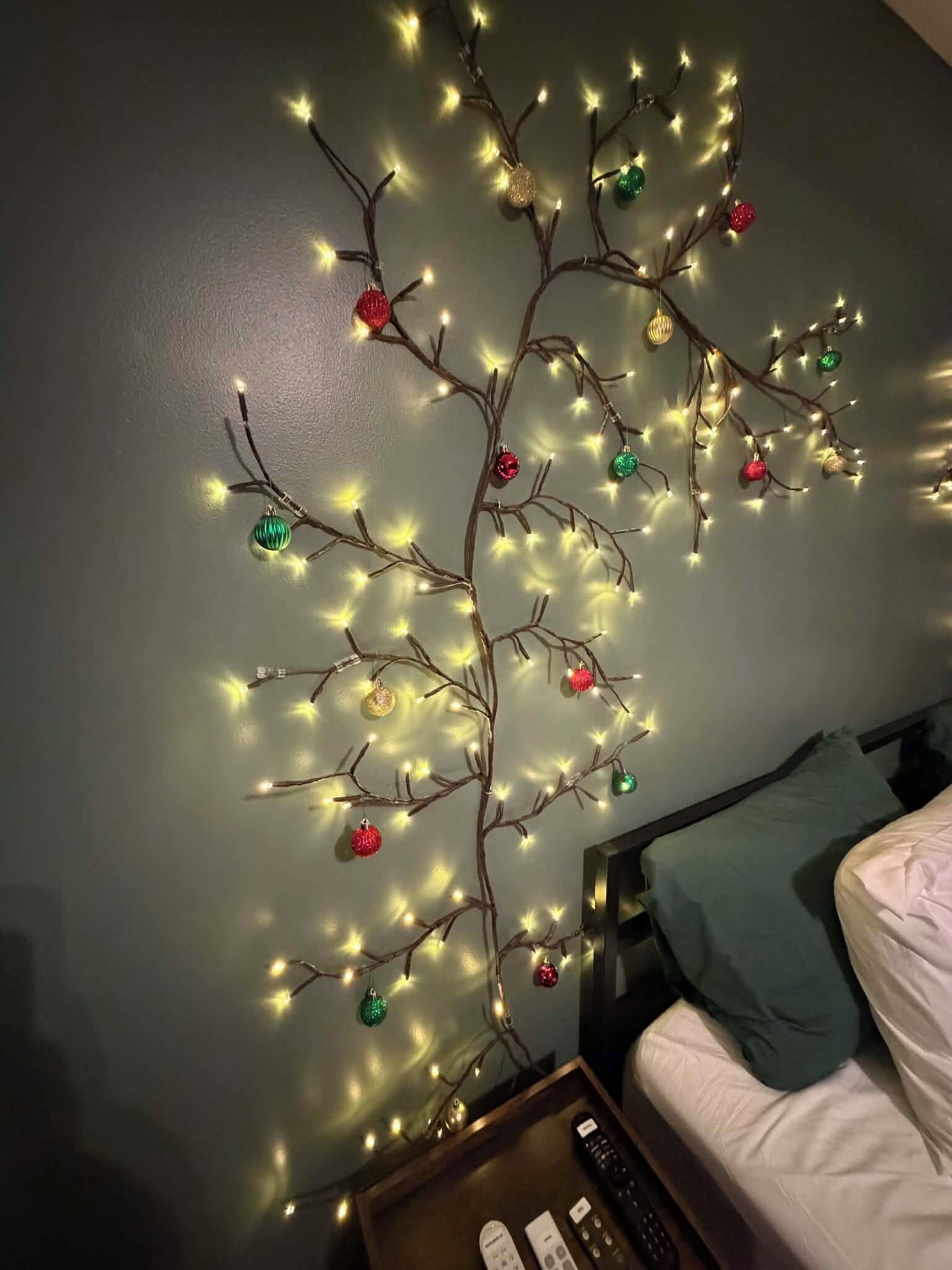 A room with a bed, a nightstand, and a wall-mounted Christmas tree decoration.