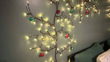 A room with a bed, a nightstand, and a wall-mounted Christmas tree decoration.