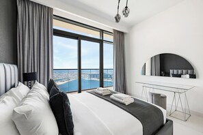 A modern hotel room with a large bed, a desk, and a view of a cityscape. - Luxury Penthouse Retreat - Private Beach, Breathtaking Palm and Marina Views (Dubai)