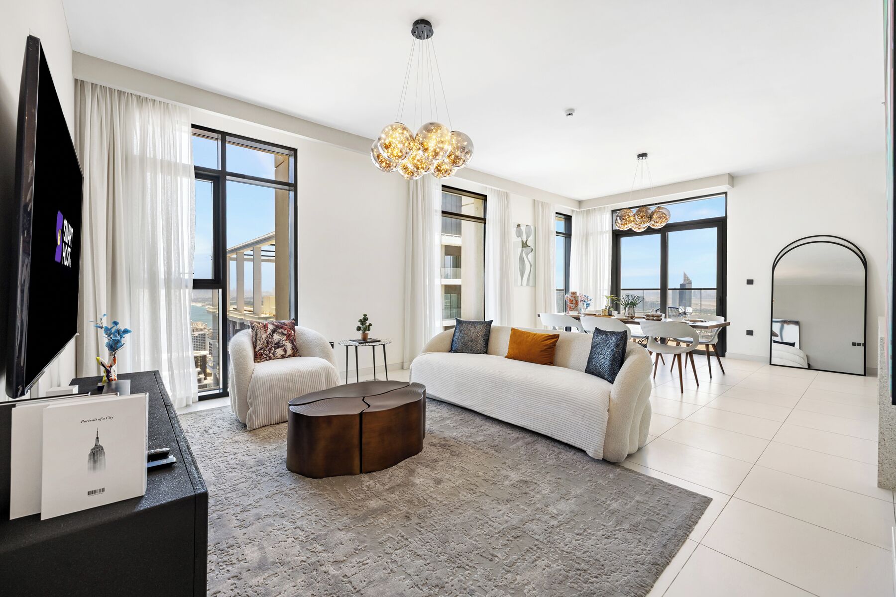 Ein geräumiges Wohnzimmer mit einer großen Couch, einem Couchtisch und einem Essbereich mit Blick auf die Stadt.