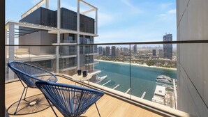 Un bâtiment moderne doté d’un balcon en verre offrant une vue sur un port de plaisance et sur le paysage urbain.