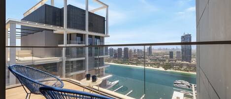 A modern building with a glass balcony overlooking a marina and cityscape.