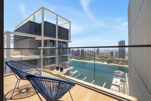 A modern building with a glass balcony overlooking a marina and cityscape. - Luxury Penthouse Retreat - Private Beach, Breathtaking Palm and Marina Views (Dubai)