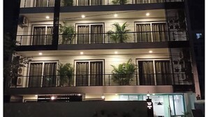 A multi-story building with balconies, large windows, and outdoor lighting. - FLORA RESIDENCY (Gurugram)