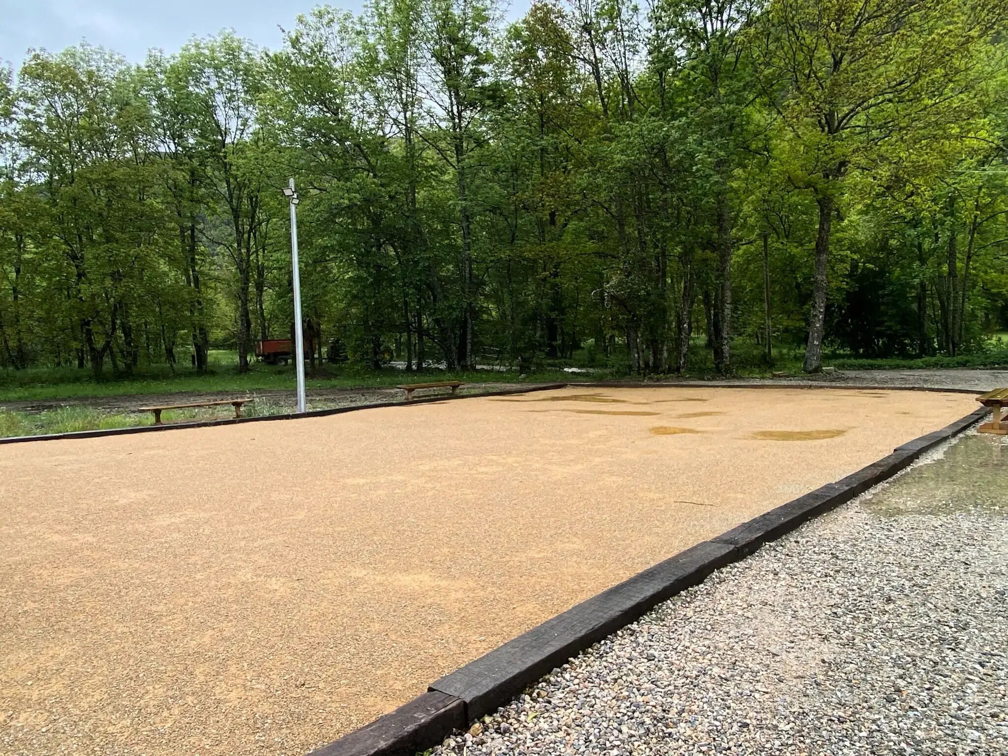 A large open area with a gravel path and a wooden bench.