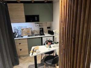 Une cuisine compacte équipée d’un four à micro-ondes, d’une machine à café et d’un petit coin repas avec une table et des chaises.