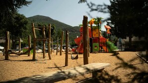Un parque infantil con tobogán, estructuras para escalar y una zona de arena.