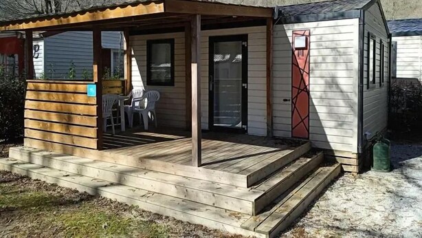 Una cabaña pequeña con terraza de madera y porche cubierto.