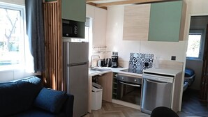 Una kitchenette compacta con refrigerador, cafetera y lavavajillas.