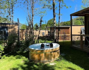 A wooden hot tub in a backyard with a wooden fence and trees. - Chalet PMR Confort - 2 bedrooms + covered terrace + air conditioning + TV for 4 people (AX LES THERMES)