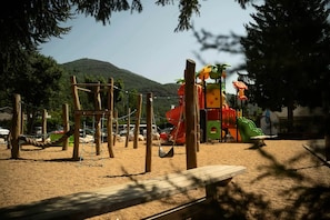A playground with a slide, climbing structures, and a sand area. - Chalet PMR Confort - 2 bedrooms + covered terrace + air conditioning + TV for 4 people (AX LES THERMES)