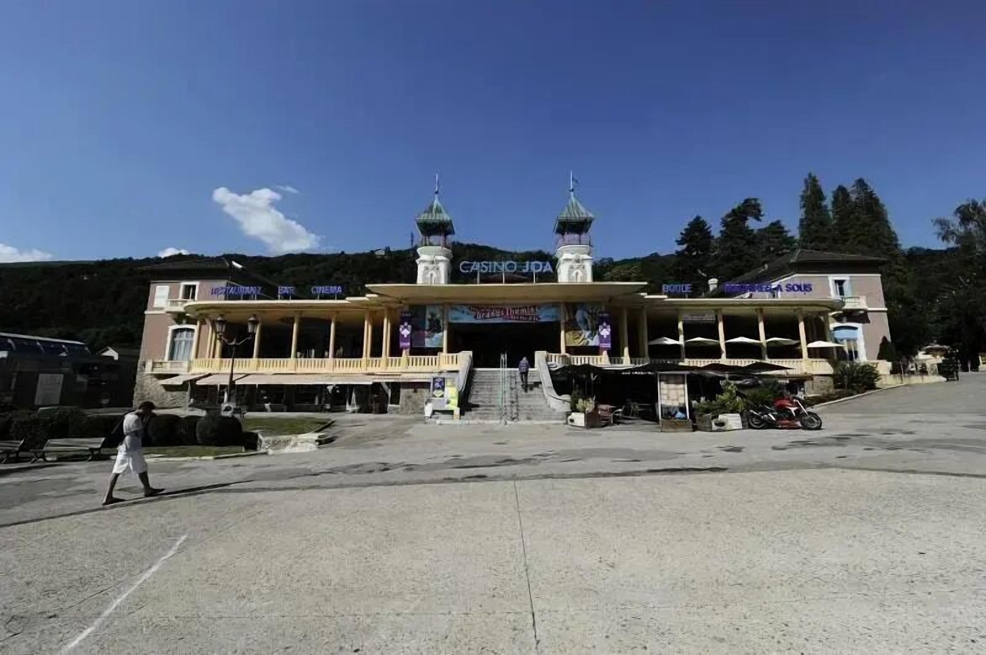 En byggnad med en central entré, två torn och ett överbyggt område med skyltar som visar texten ”CASTINO JDA” och ”CINEMA”.