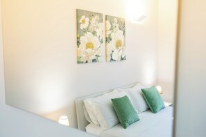 Un dormitorio con cama, almohadas y dos cuadros colgados en la pared.