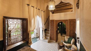A room with a patterned floor, a staircase, a chair, and a hanging light fixture. - Riad Mint  (Marrakech)