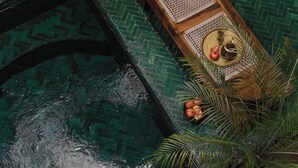 A boat on a green-tiled pool with a woven seat and a woven basket containing fruits. - Riad Mint  (Marrakech)
