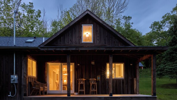 Eine Holzhütte mit Veranda, zwei Stühlen und einem Tisch.