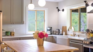 Eine moderne Küche mit einer Holzinsel, Edelstahlgeräten und Blick auf Grün durch große Fenster.