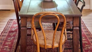 Ein Essbereich mit einem Holztisch, sechs Stühlen, einer Schüssel in der Mitte und einer hängenden Leuchte.