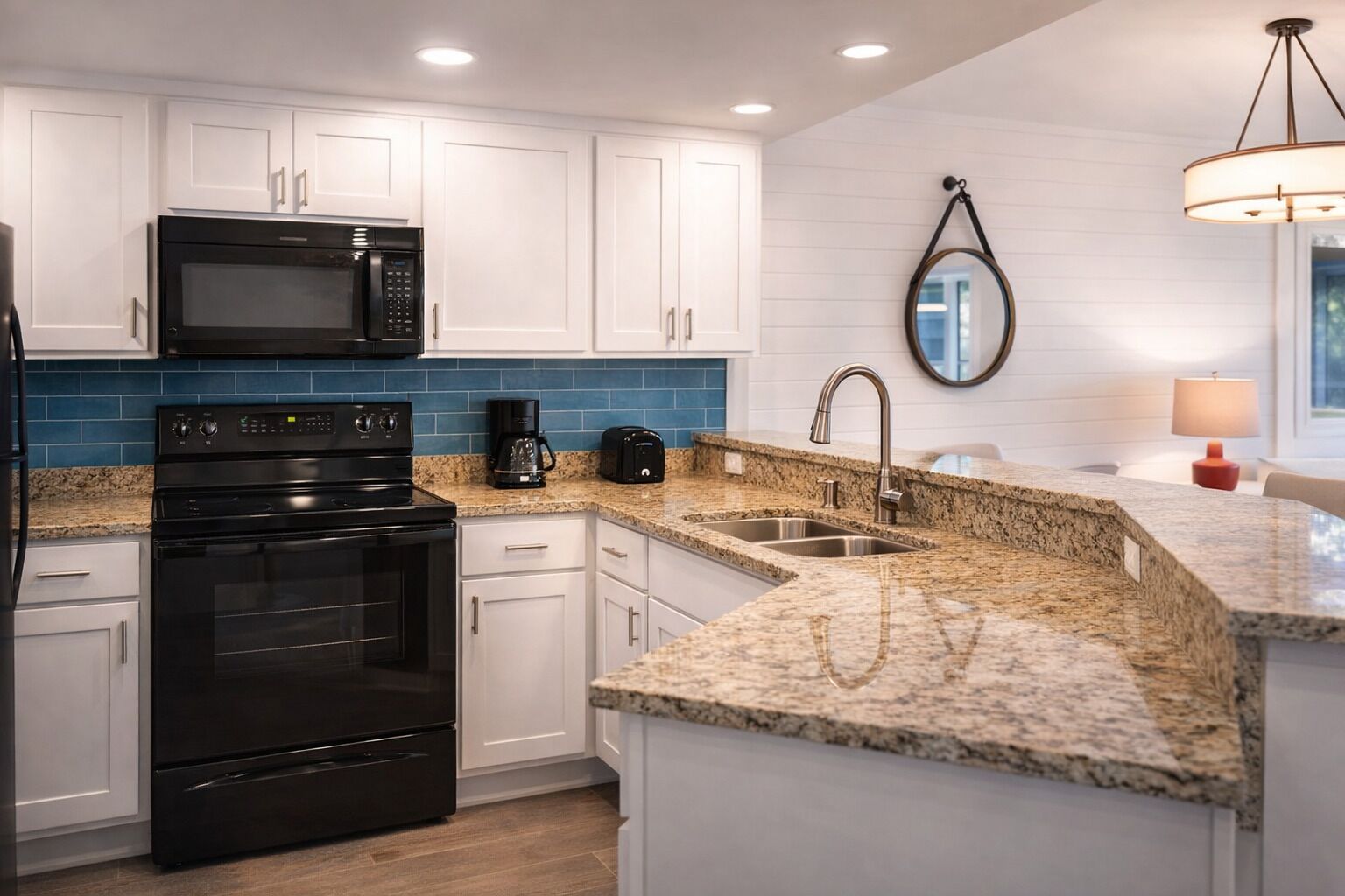 A modern kitchen with white cabinets, a black stove, a microwave, a coffee maker, and a sink.