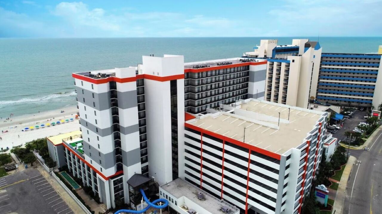 Un hôtel à plusieurs étages, doté d’un parking et offrant une vue sur la plage.
